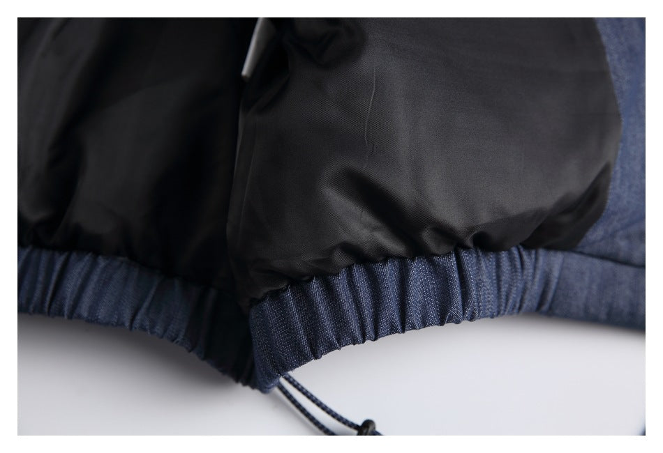 Close-up of the jacket's black lining, gathered blue denim hem, and dangling drawcord.