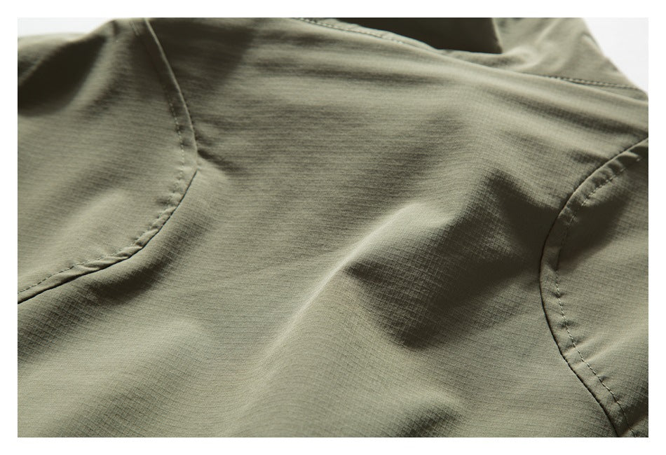 Close-up of olive-gray garment fabric with curved stitched seams and subtle surface texture.