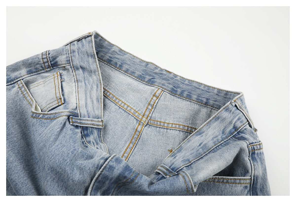 Close-up of light-wash jeans showing the waistband, belt loops, seams, and front pocket opening.