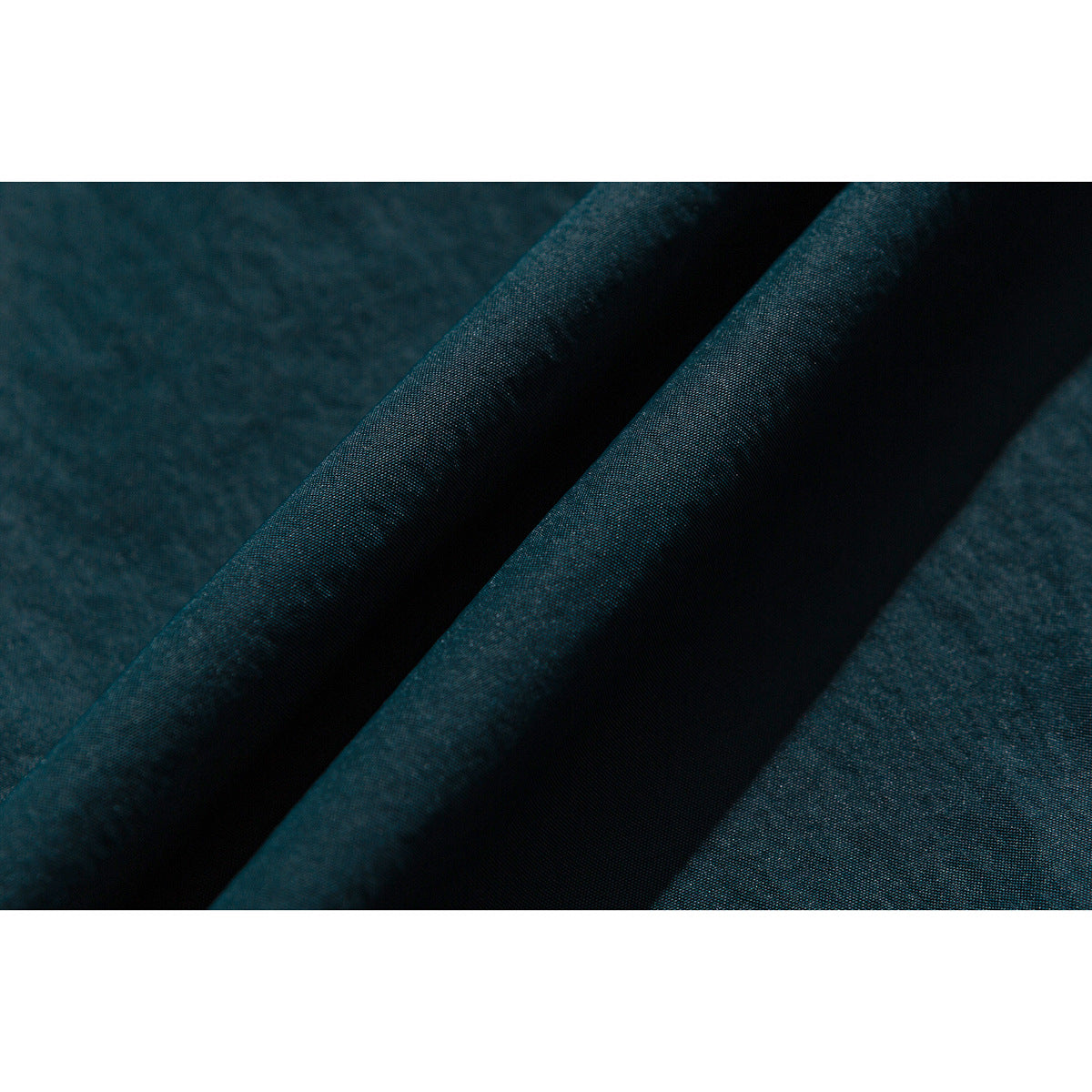 Close-up of deep teal jacket fabric arranged in soft folds.