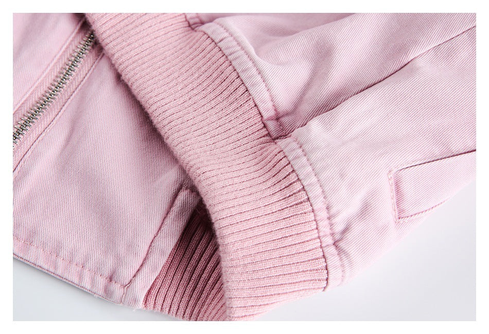 Close-up of a pink garment showing a metal zipper, ribbed trim, seams, and a pocket detail.
