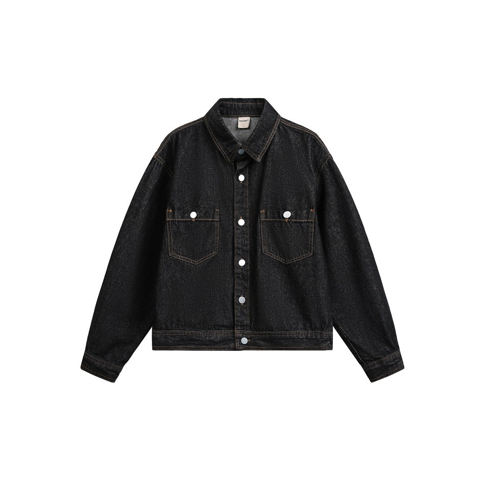 Black washed denim trucker jacket, front view, with silver buttons, two chest pockets and tan topstitching