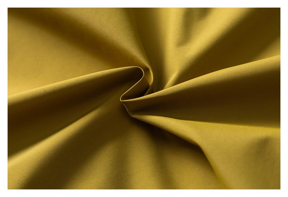 Close-up of mustard-yellow fabric arranged in soft folds.