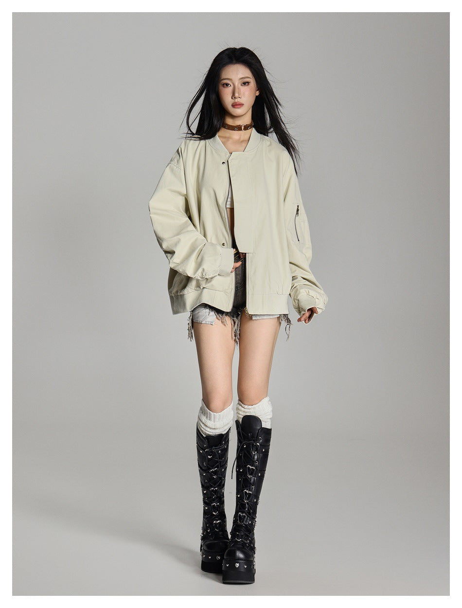 Model in a loose beige bomber jacket with ribbed hem and sleeve zip pocket, styled with denim shorts and tall boots