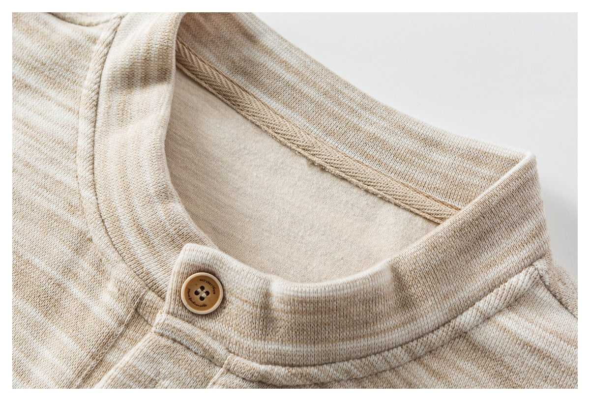 Close-up of a beige heathered knit neckline with a small tan button and stitched seams.
