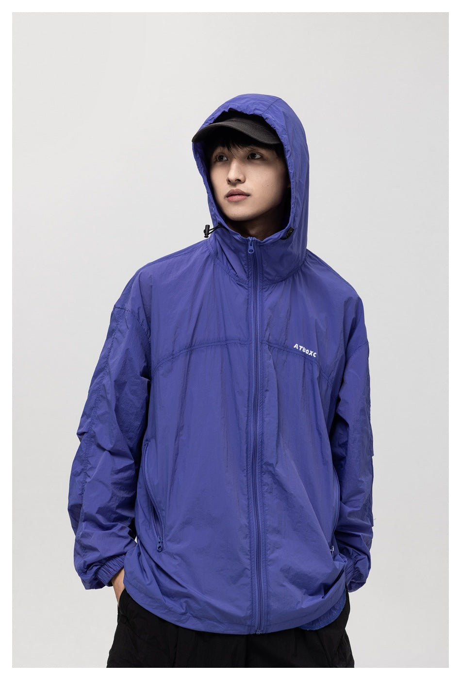 Front view of a model wearing a blue-purple hooded zip jacket with elastic cuffs and zip pockets.