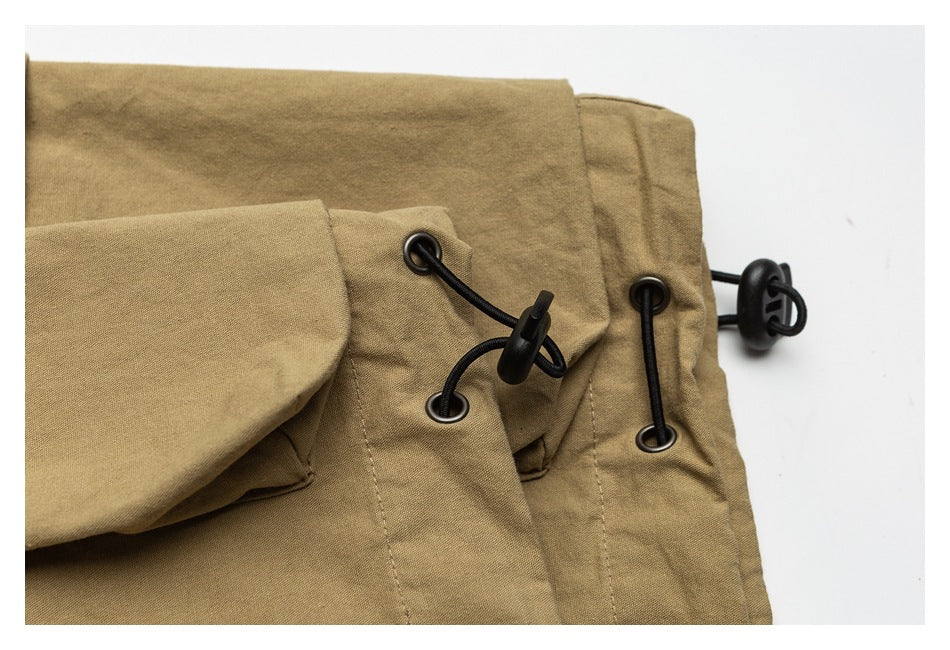 Close-up of tan garment panels with black cord toggles and metal eyelets.