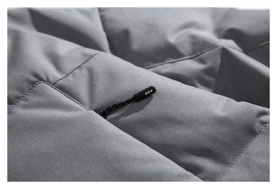 Close-up of a black drawcord toggle emerging from a seam on gray jacket fabric.