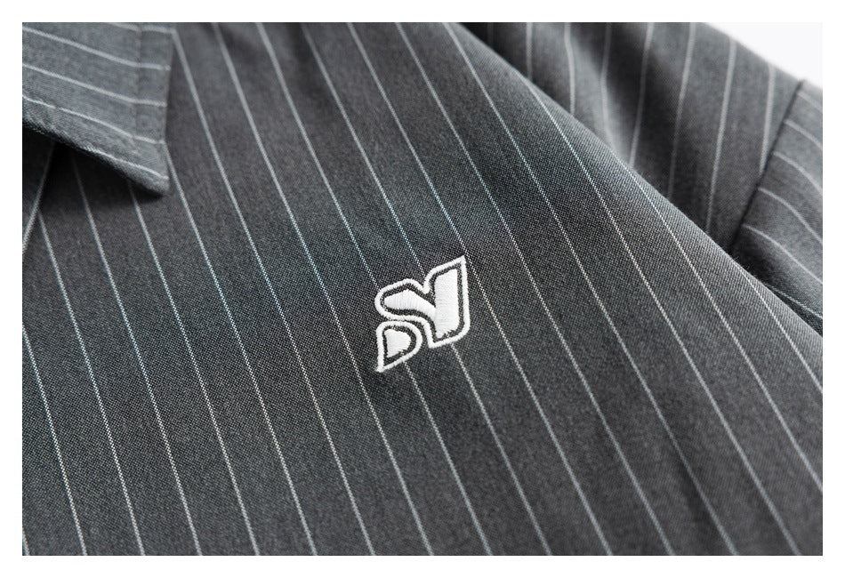 Close-up of a white embroidered emblem on the charcoal pinstripe shirt.