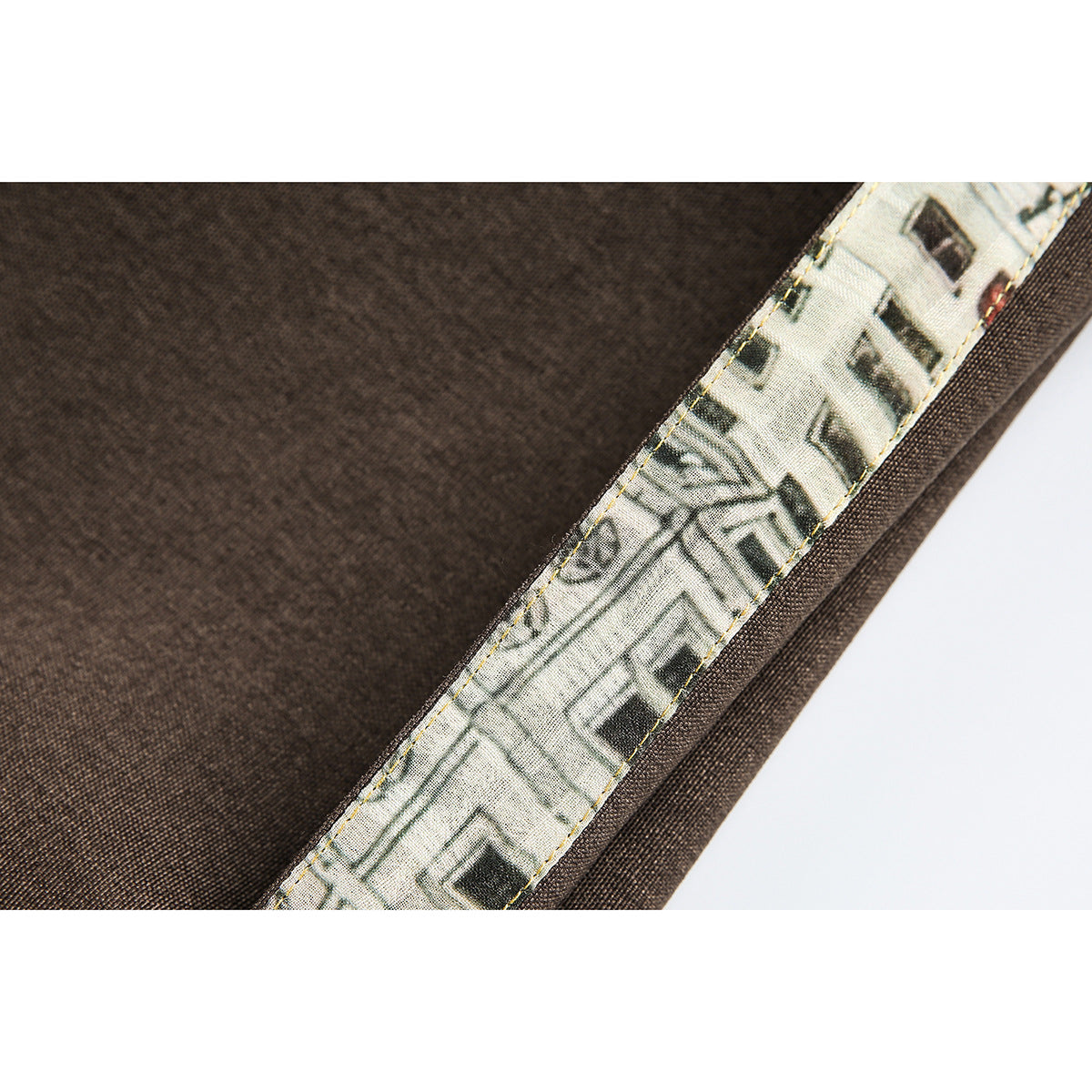 Close-up of a brown garment seam finished with a narrow strip of illustrated cream lining.