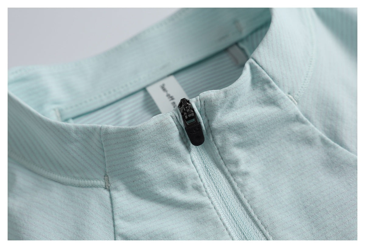 Close-up of the pale aqua top's stand collar, black front zipper, and fine stripe texture.