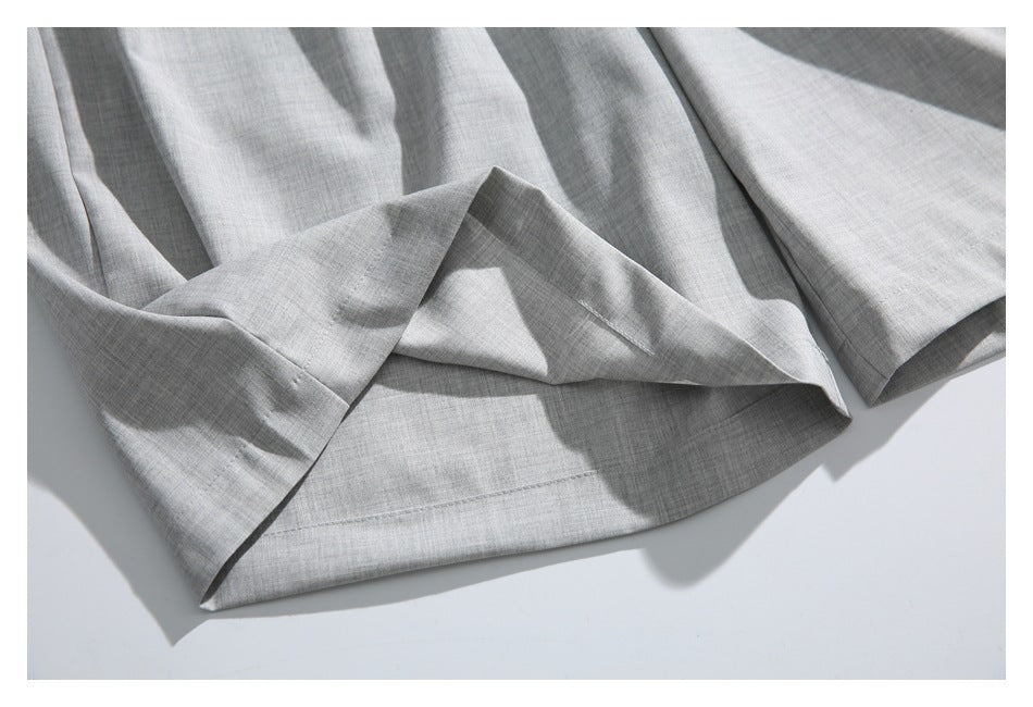 Close-up of the hem and folded leg opening of light gray trousers.