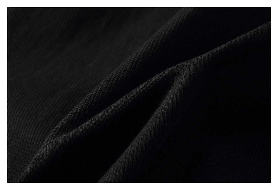 Close-up of black ribbed fabric gathered into folds, showing its fine vertical texture.