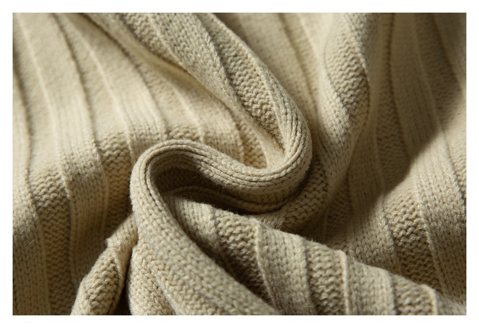 Close-up of beige ribbed knit fabric folded to show its texture and construction.