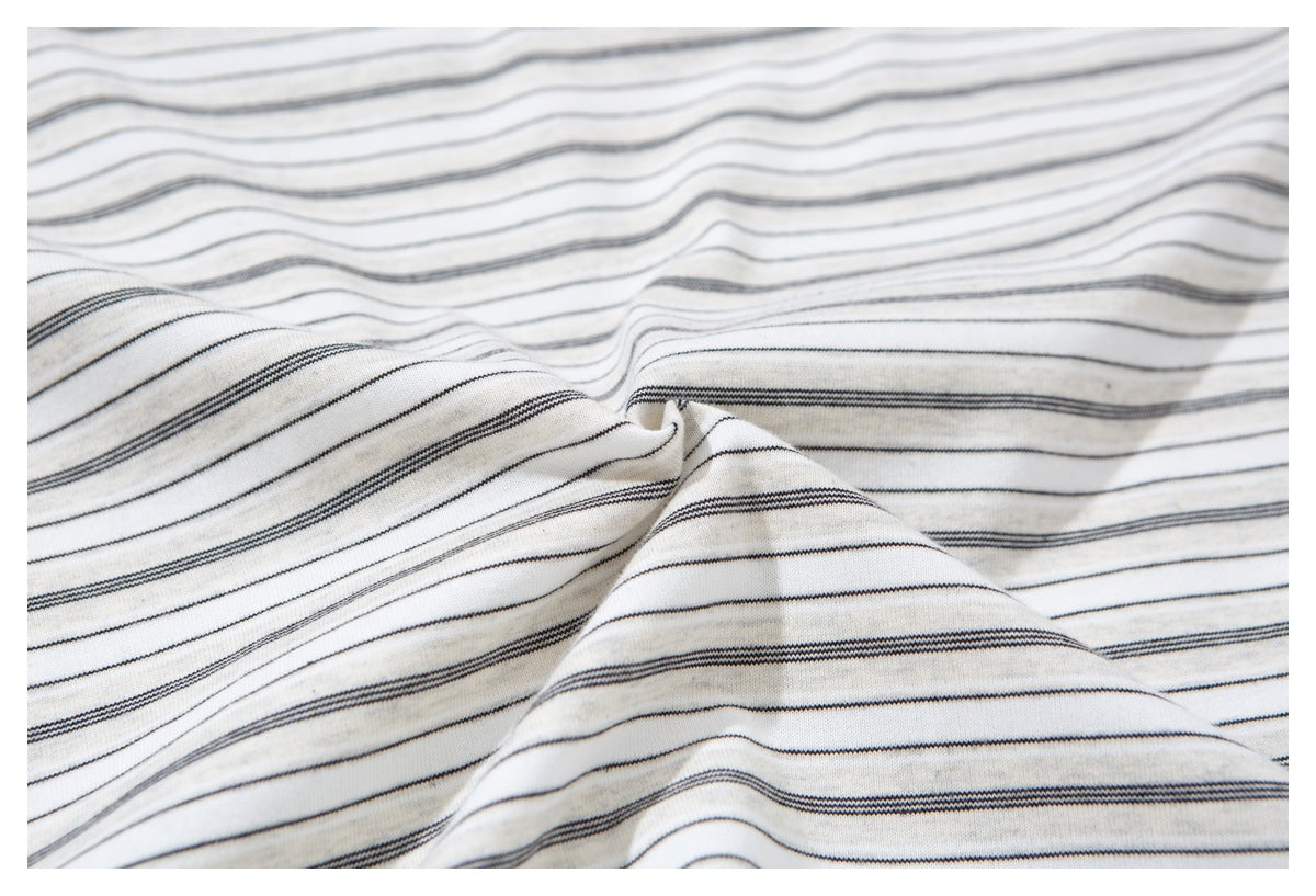 Close-up of the ivory shirt fabric, showing thin dark horizontal stripes and its surface texture.