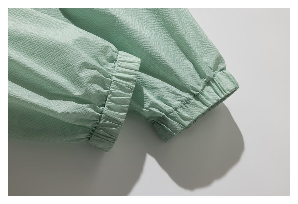 Close-up of a mint-green sleeve showing a gathered elastic cuff and seam.