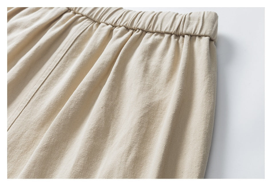 Close-up of beige trousers showing the gathered elastic waistband and stitched seam.
