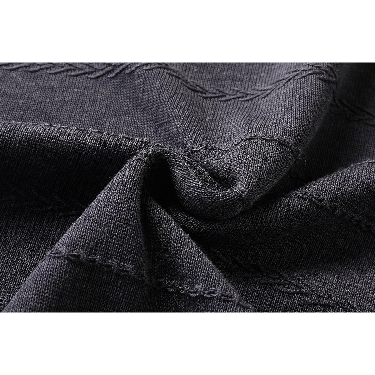 Close-up of charcoal knit fabric with raised horizontal stitched lines and a folded section.