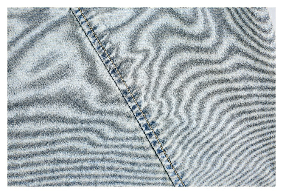 Close-up of light-wash denim showing a diagonal double-stitched seam.