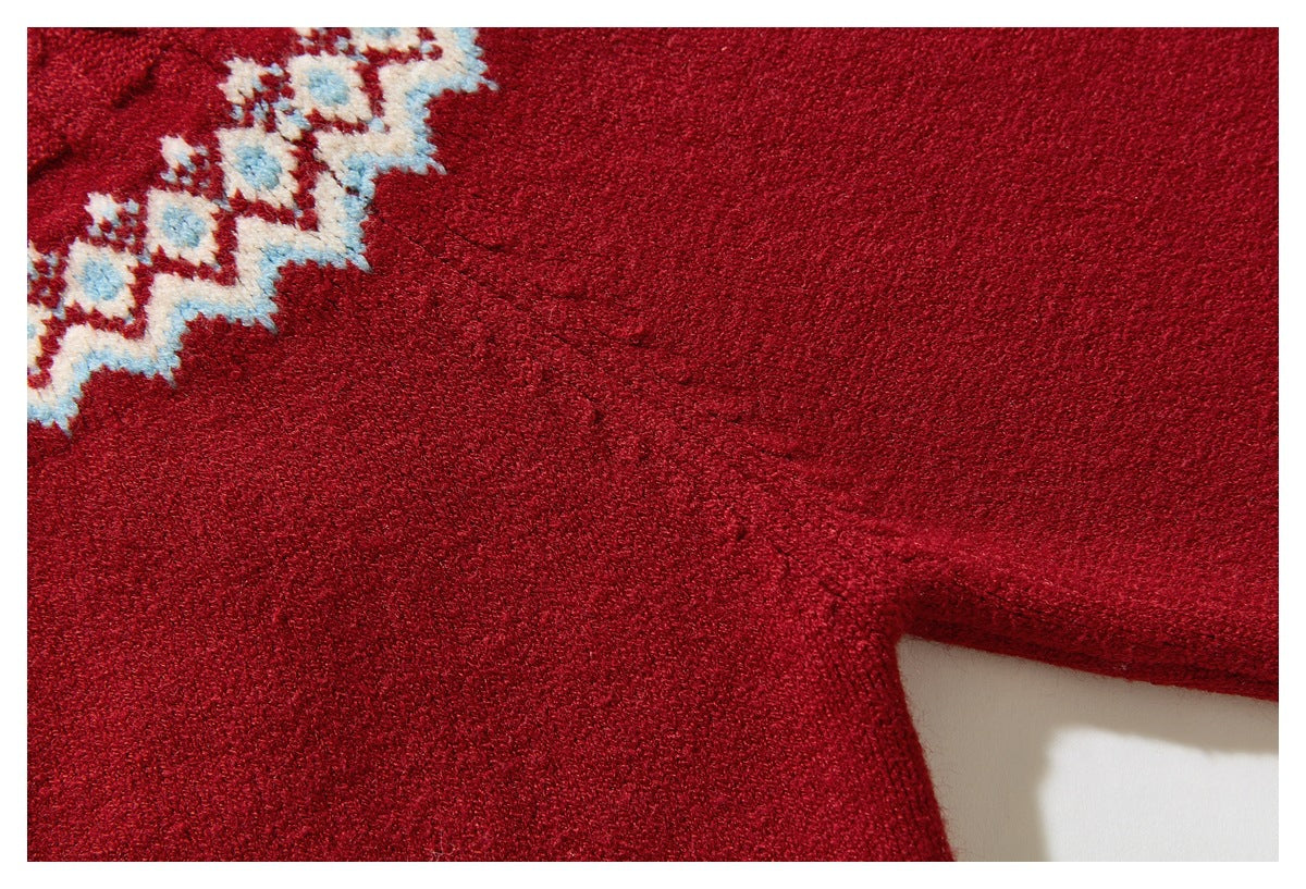 Close-up of red sweater knit with part of a cream-and-blue geometric band visible at the edge.