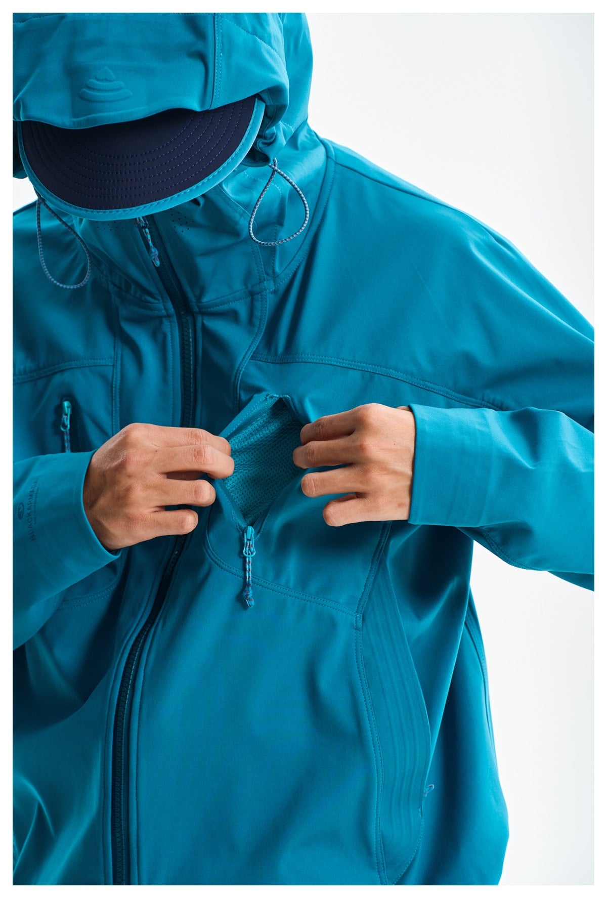 Close-up of the teal jacket's chest pocket opened to show mesh lining and a zip closure.