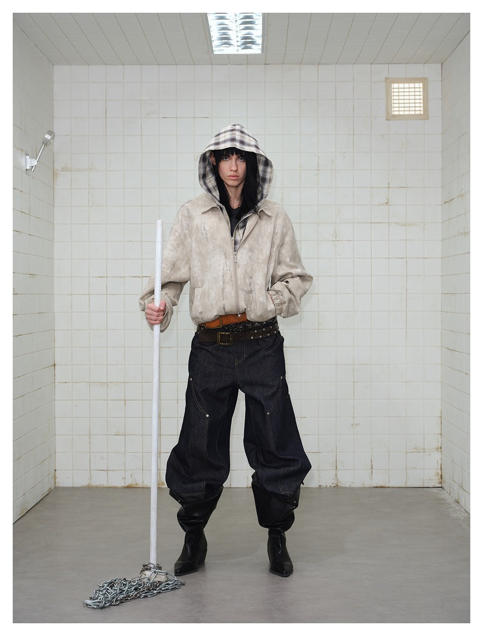 Front view of a model in a light beige mottled zip jacket with a plaid hood and dark baggy jeans.