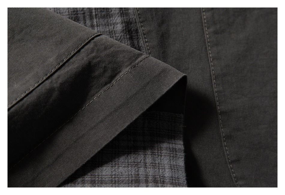 Close-up of a dark garment edge with visible stitching and a gray plaid inner panel.