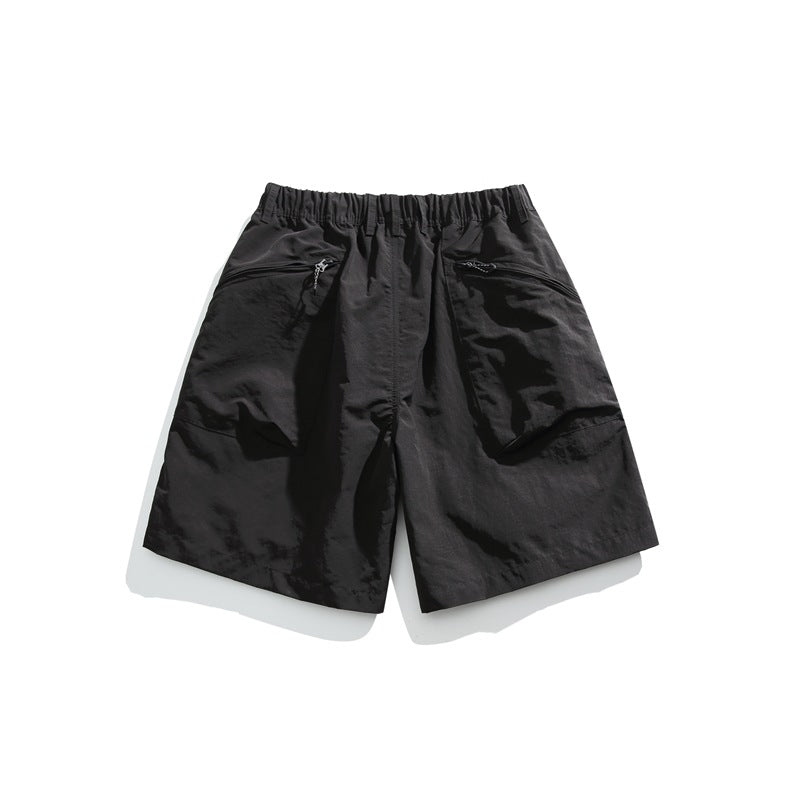 Black shorts laid flat, with an elastic waistband and two slanted zip pockets.