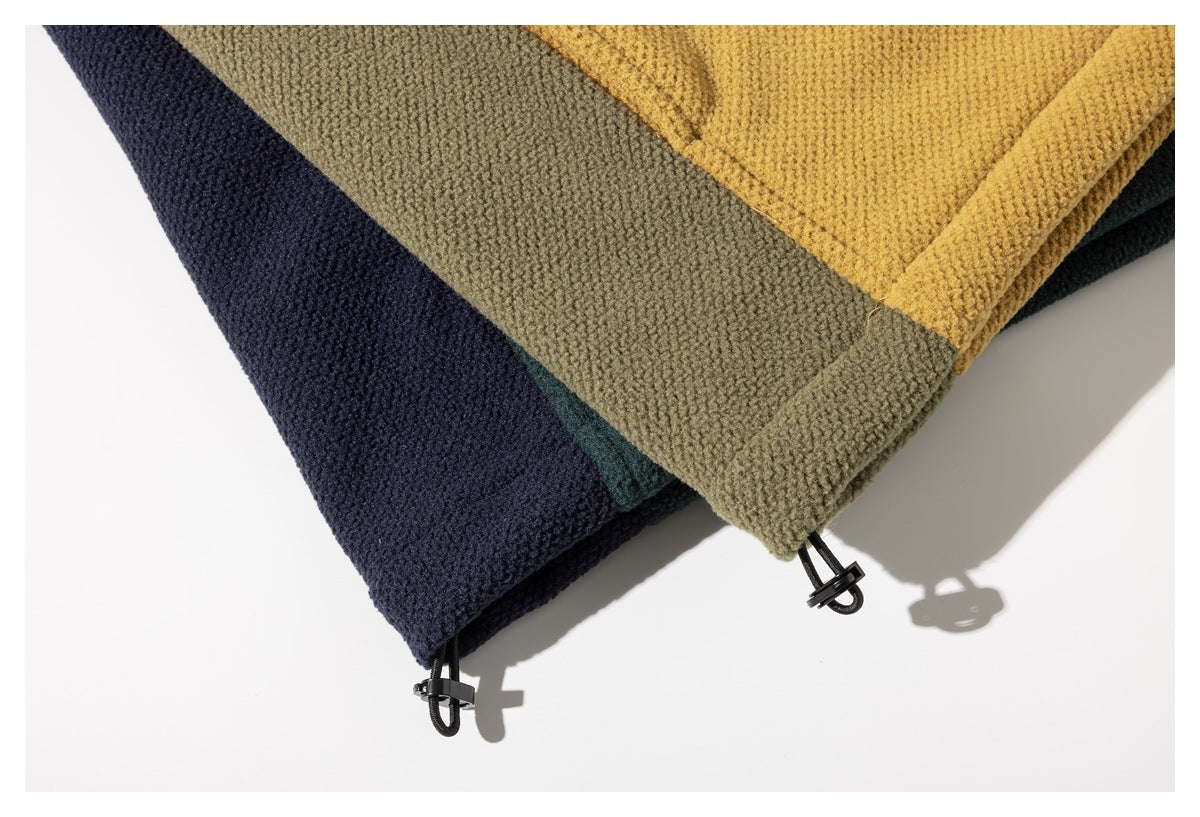 Close-up of layered mustard, olive, navy, and dark green jacket hems with black drawcord toggles.