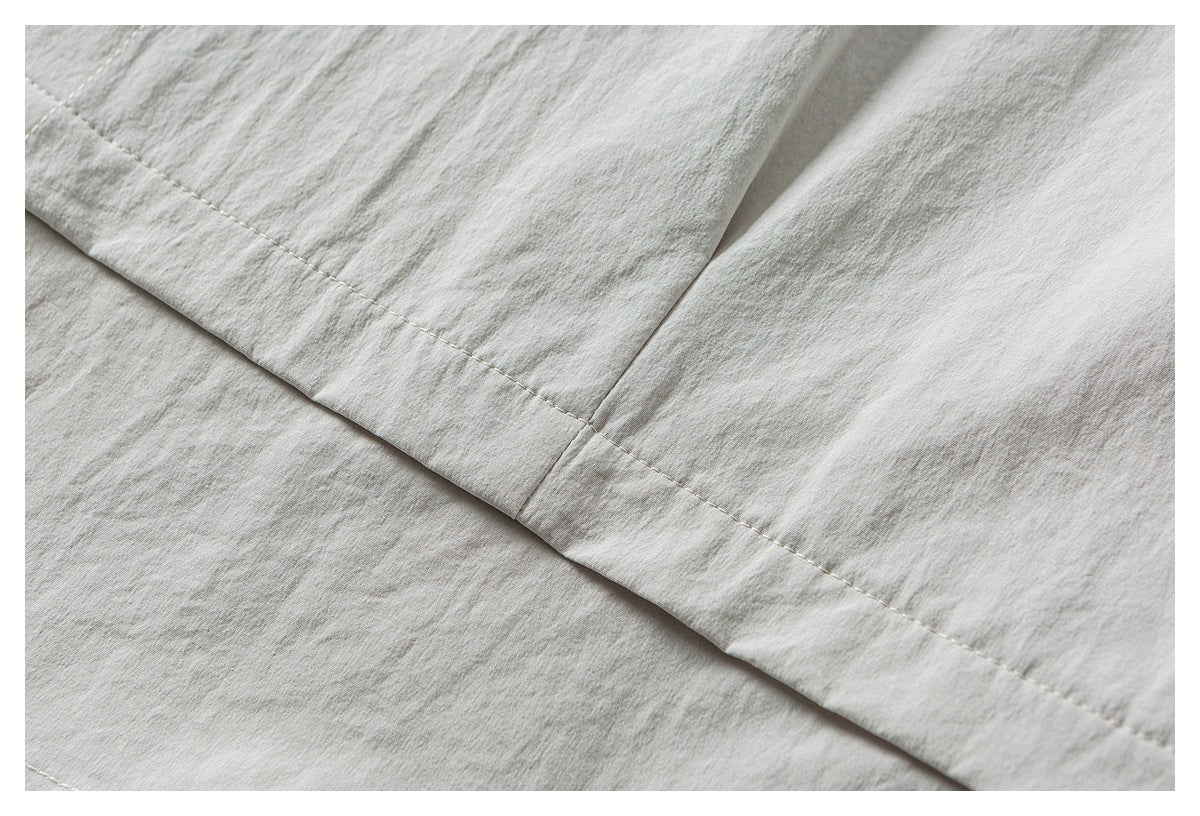 Close-up of a folded hem with a single row of stitching on light gray-beige fabric.