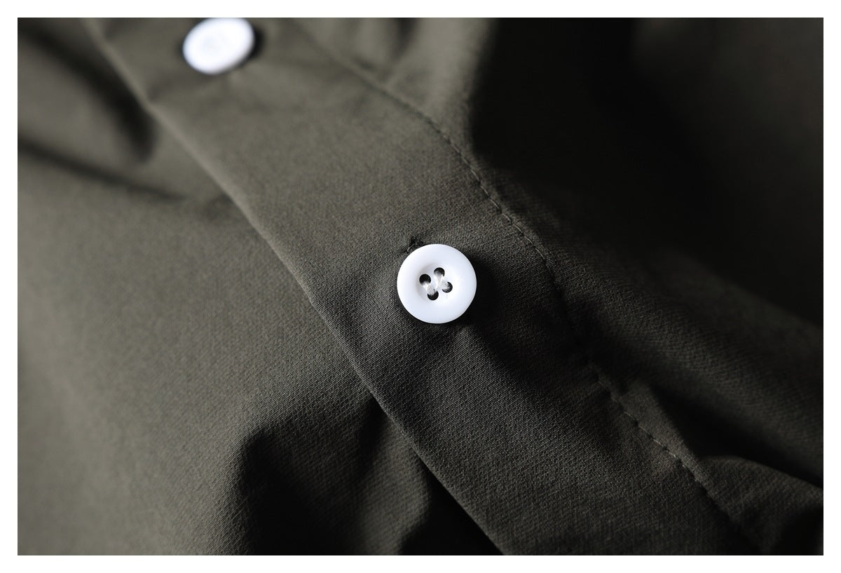 Close-up of a white button on the placket of a dark olive garment.