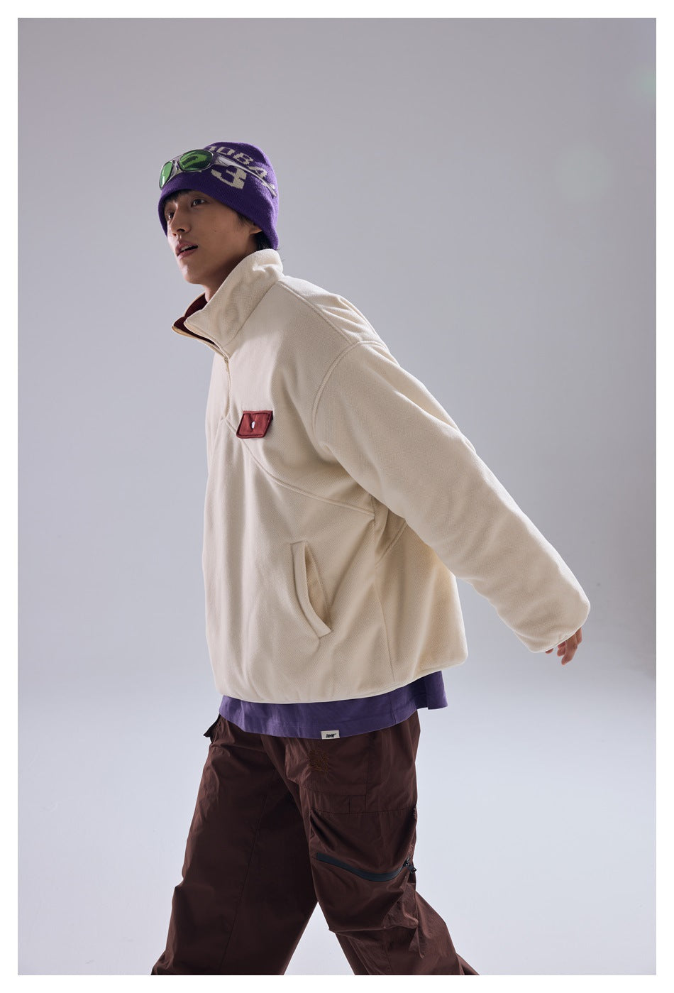Side view of a model wearing an ivory quarter-zip pullover with a burgundy chest pocket.