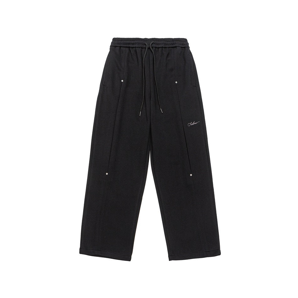 Black wide-leg sweatpants flat lay with drawstring waist, front seams, metal snap details and small script embroidery