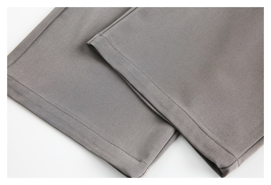 Close-up of gray trouser legs and stitched hems laid on a white background.