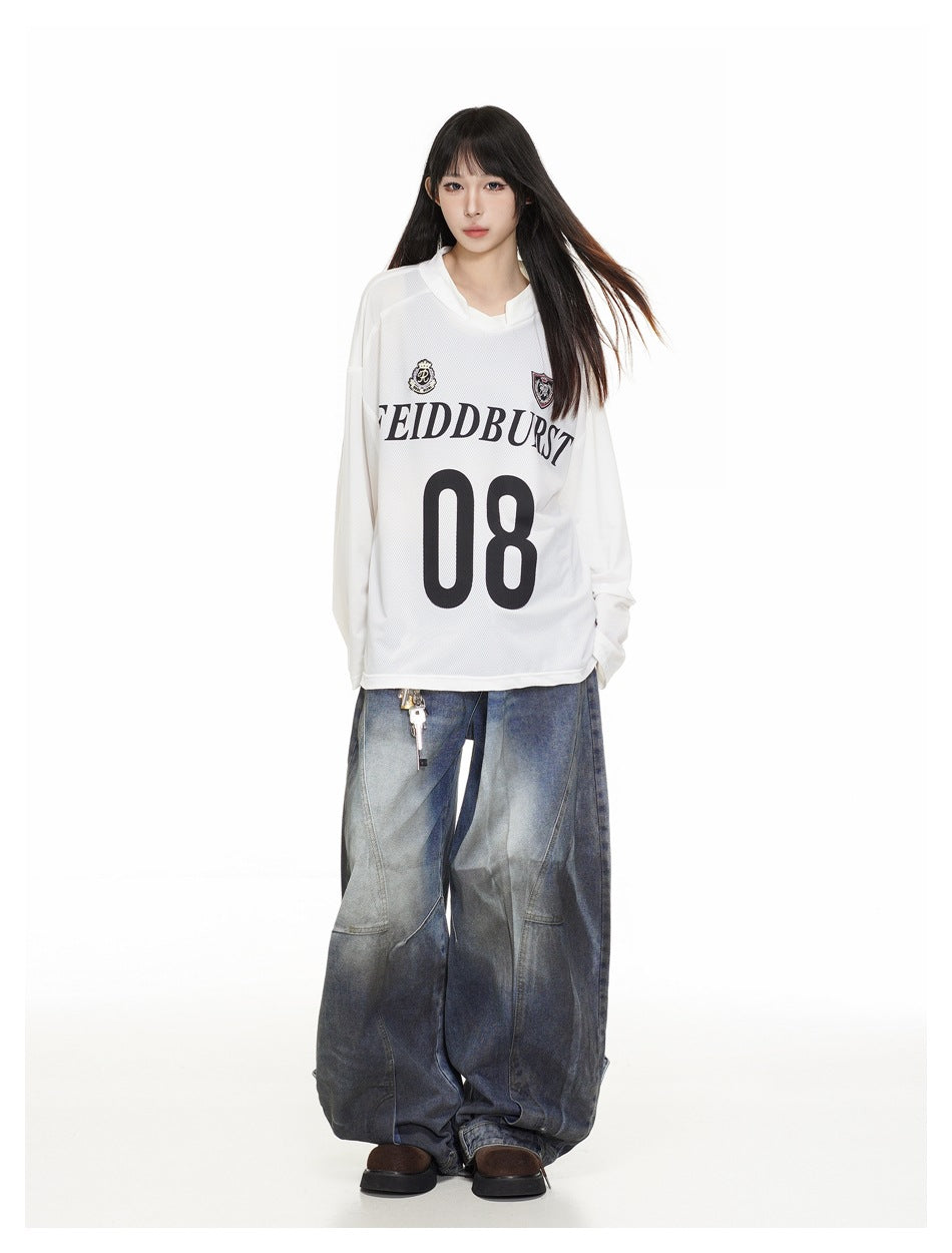 Model wearing the white oversized long-sleeve jersey-style top with large 08 print and wide-leg faded blue jeans