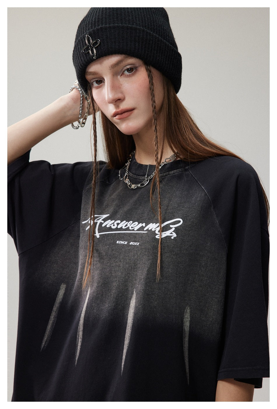 Close view of a model wearing a black oversized T-shirt with a faded front graphic and white script.