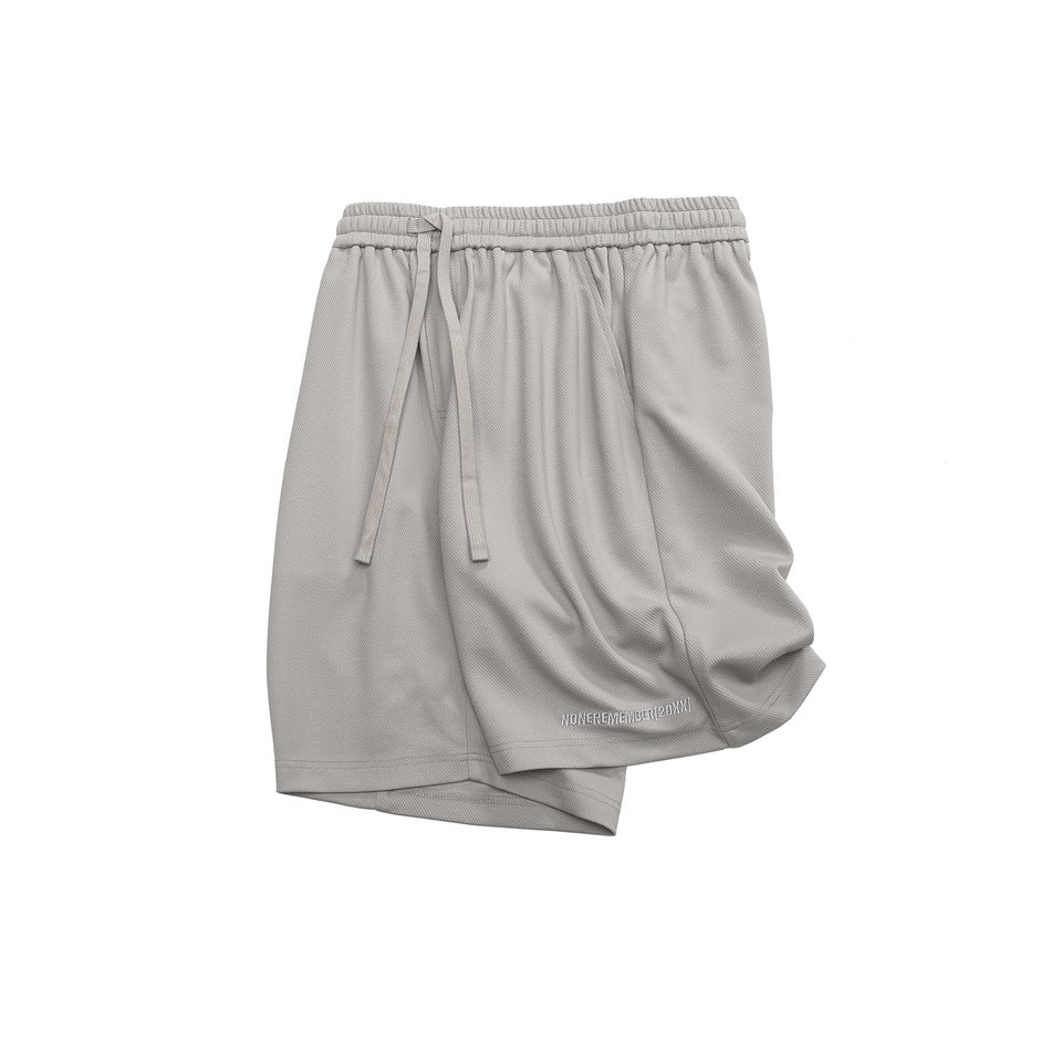 Light gray shorts laid flat, with an elastic drawstring waist and small white lettering near the hem.