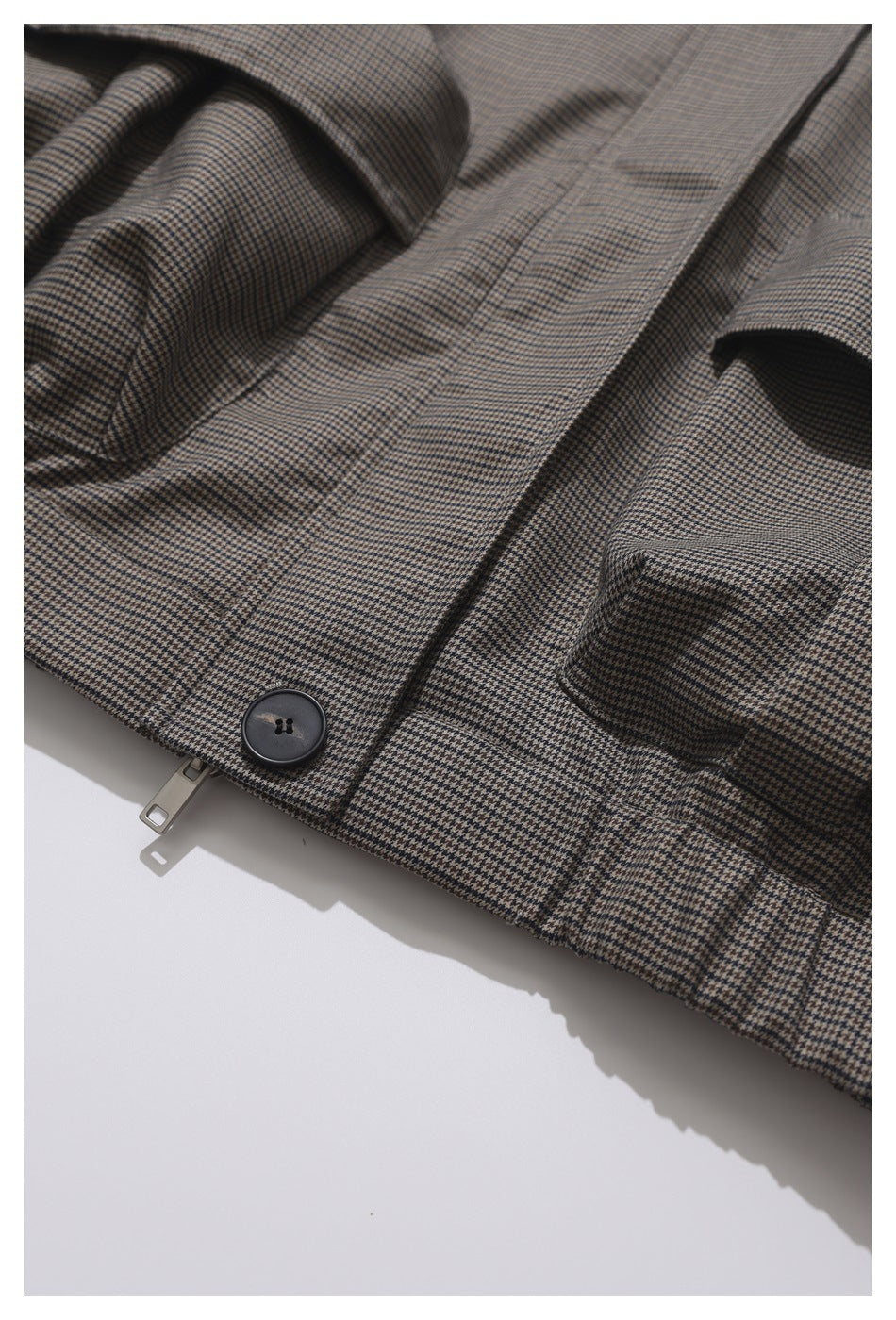 Close-up of the houndstooth jacket's front zipper, button, and flap pocket.