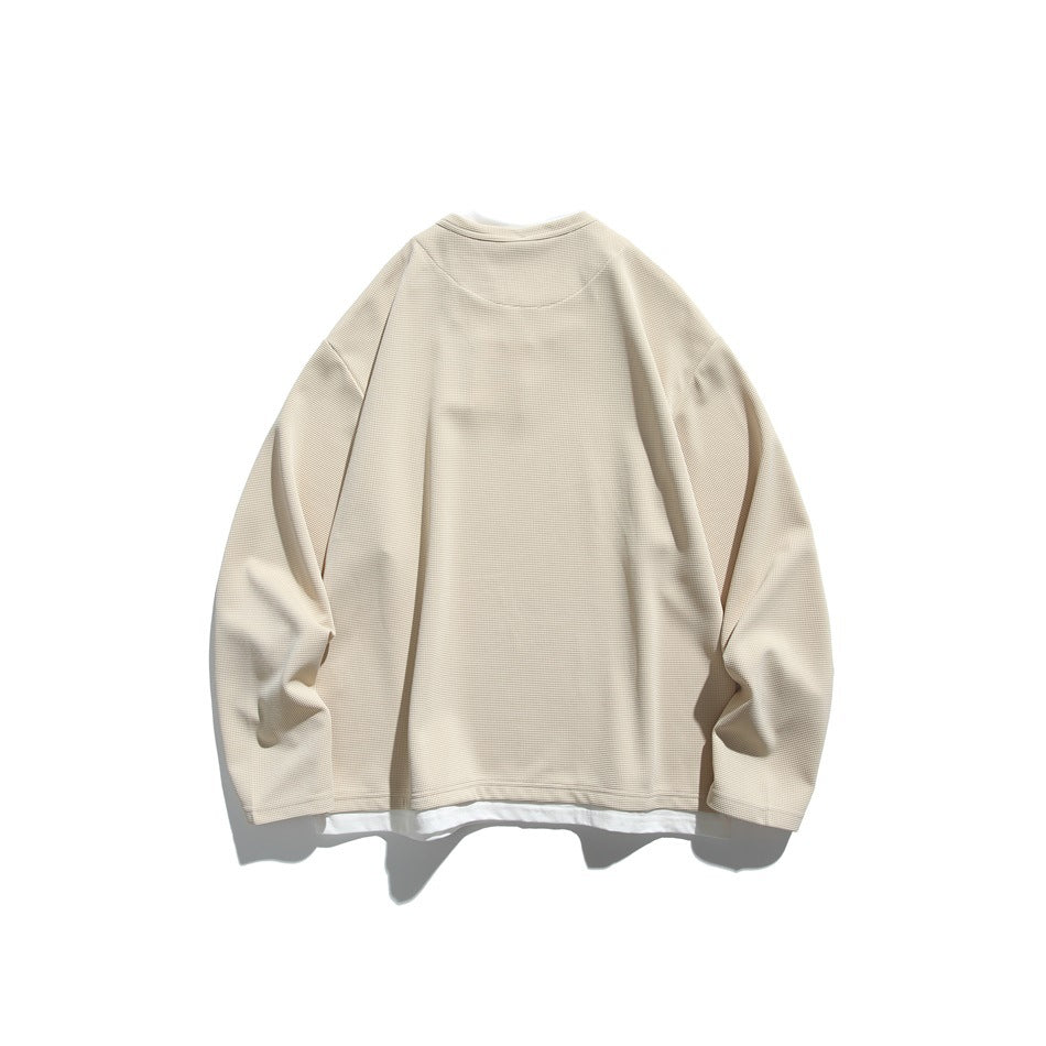 Back view of a cream long-sleeve top with a simple neckline and a white layer visible below the hem.