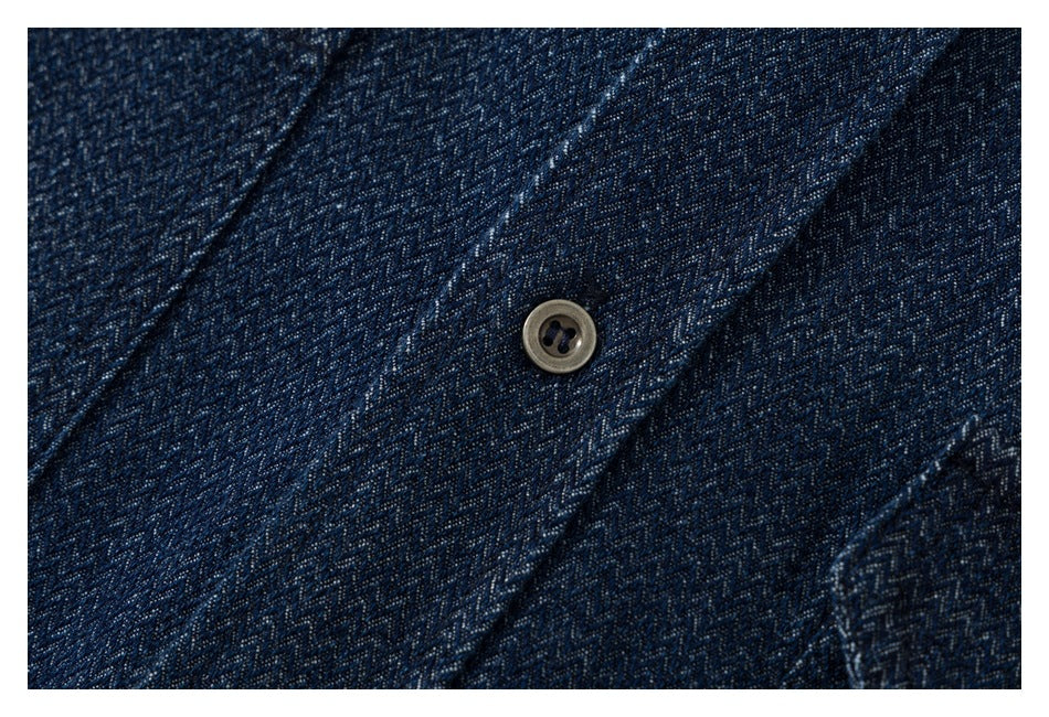 Close-up of a brown button and stitching on the dark navy patterned shirt placket.