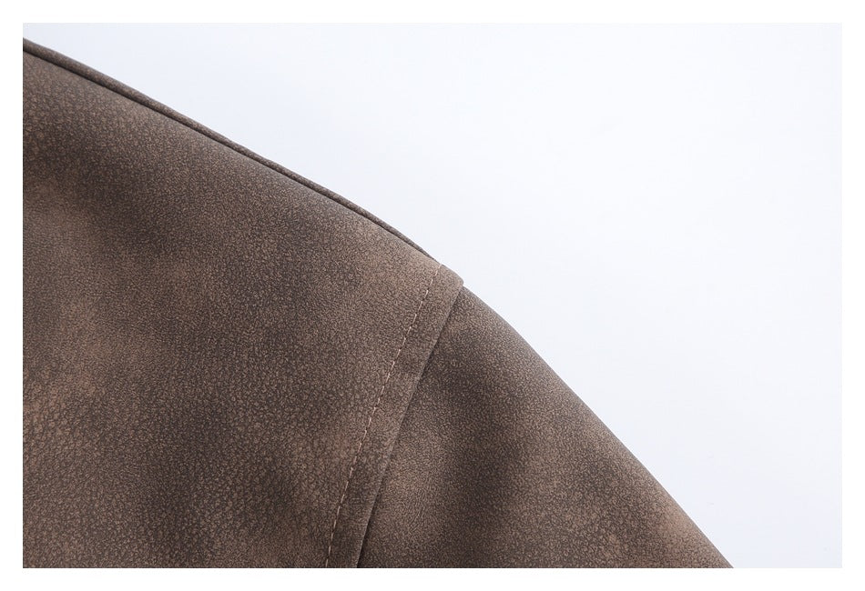 Close-up of a brown jacket shoulder with a curved seam and mottled surface.