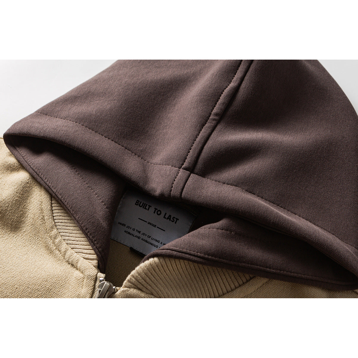 Close-up of a brown hood and beige ribbed collar, showing the zipper area and an inner label reading “BUILT TO LAST.”