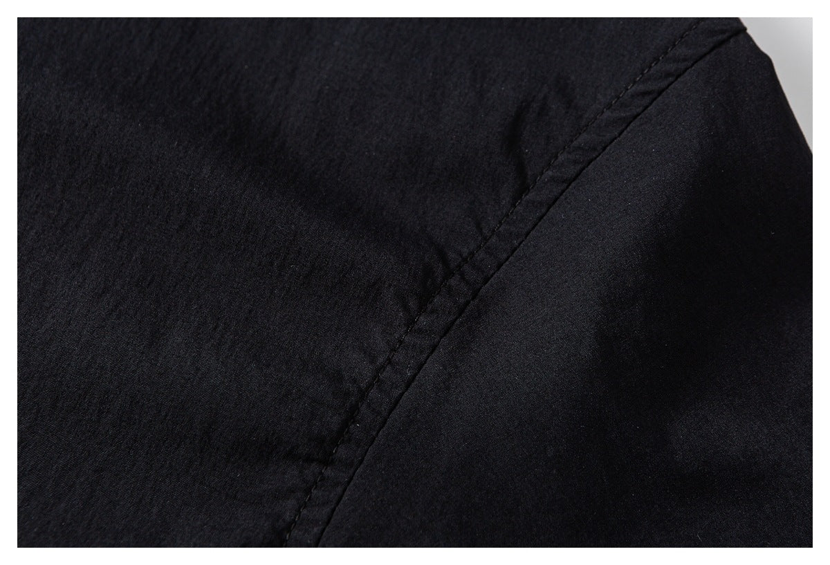 Close-up of black garment showing a curved seam between textured and smoother fabric panels.