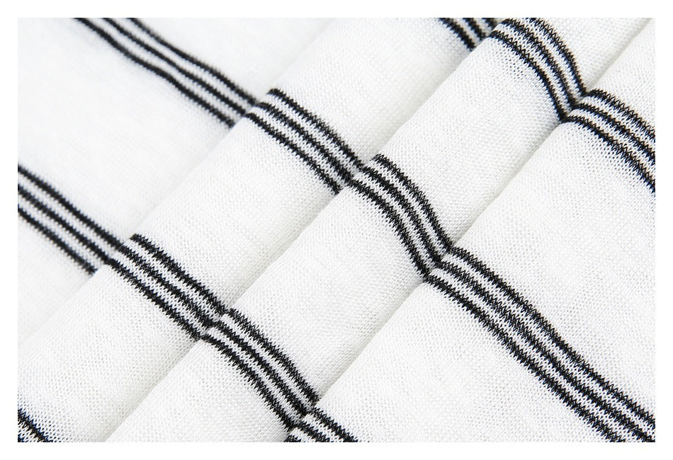 Close-up of folded white fabric showing narrow black stripes and a fine knit texture.