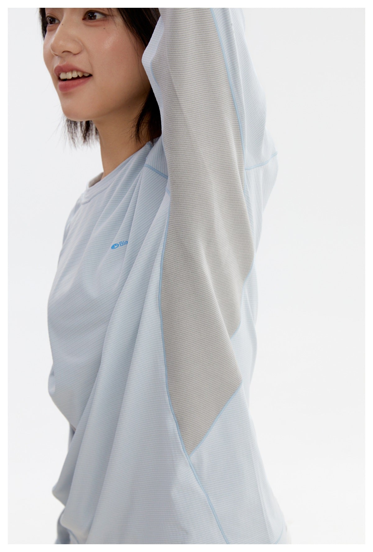 Close-up of the pale blue shirt's gray underarm panel, blue seam piping, and small chest logo.