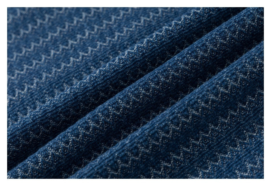 Macro view of blue fabric showing a repeating light zigzag weave and textured folds.