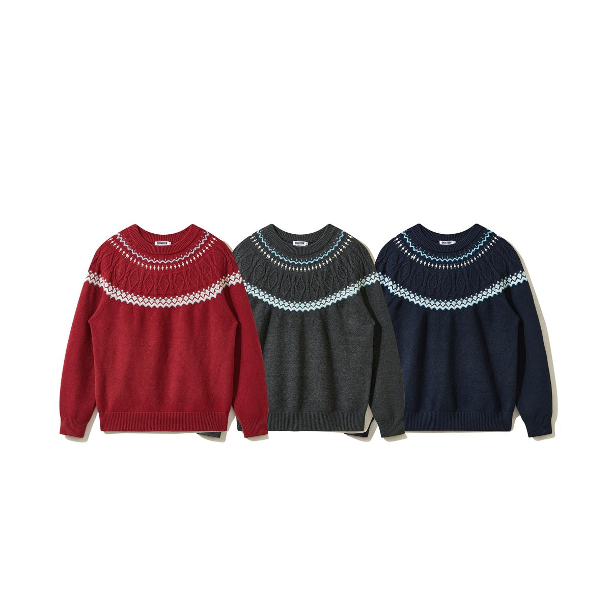 Three crewneck sweaters shown from the front in red, charcoal gray, and navy, each with a patterned cable-knit yoke.
