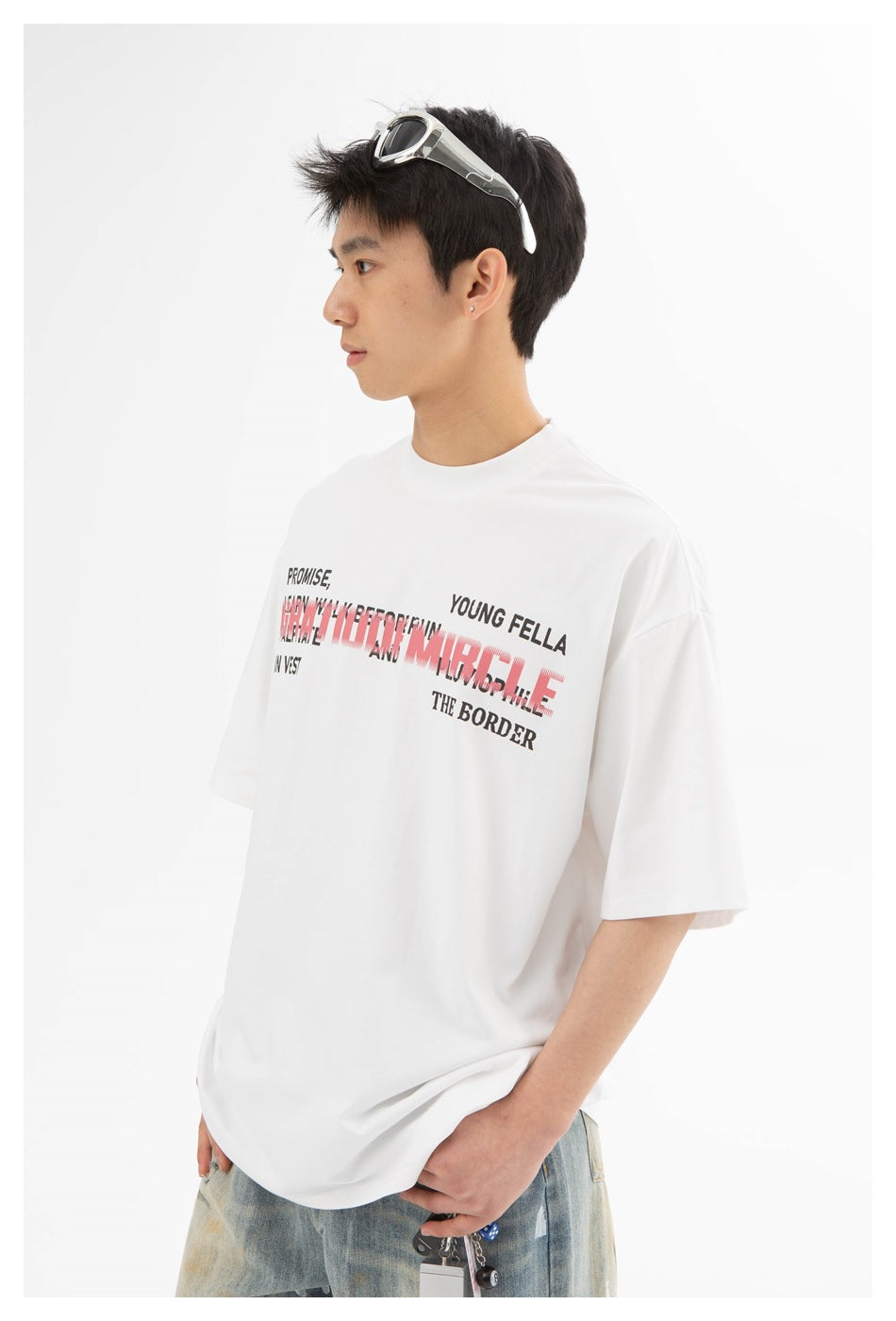 Closer side view of a model wearing a white T-shirt with layered black and pink chest lettering.