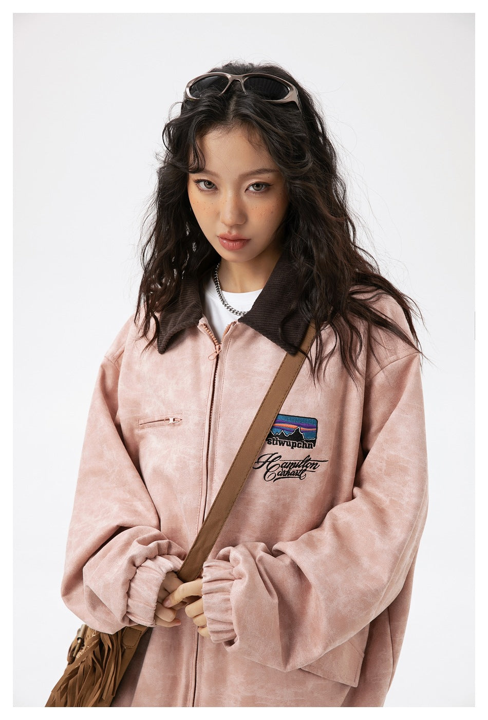Close-up of the jacket's dark collar, pink zipper, and colorful embroidered chest patch.