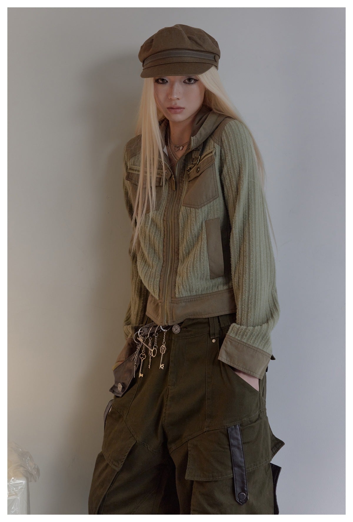 Three-quarter view of a model wearing a sage ribbed zip jacket with tan panels and dark olive cargo pants.